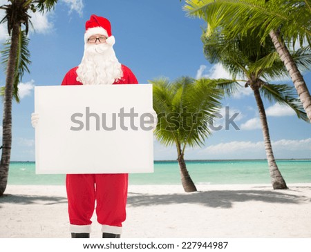 christmas, holidays, advertisement and people concept - man in costume of santa claus with white blank billboard over tropical beach background