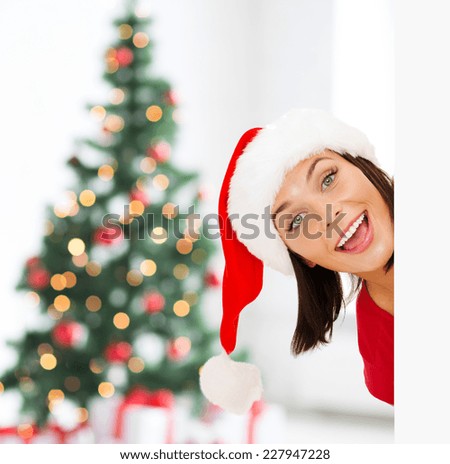x-mas, people, advertisement and sale concept - happy woman in santa helper hat with blank white board over living room and christmas tree background