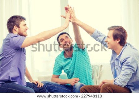 teamwork, friendship and happiness concept - smiling male friends giving high five at home