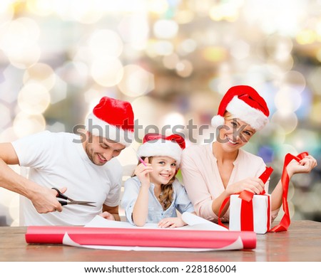 christmas, holidays, family and people concept - happy mother, father and little girl in santa helper hats with gift box and scissors over lights background