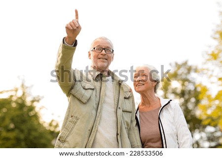 family, age, tourism, travel and people concept - senior couple pointing finger in park