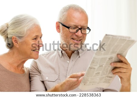 family, holidays, age and people concept - happy senior couple reading newspaper at home