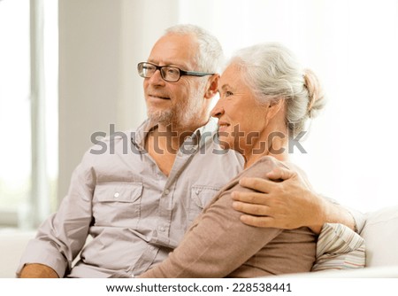 family, holidays, age and people concept - happy senior couple sitting on sofa at home