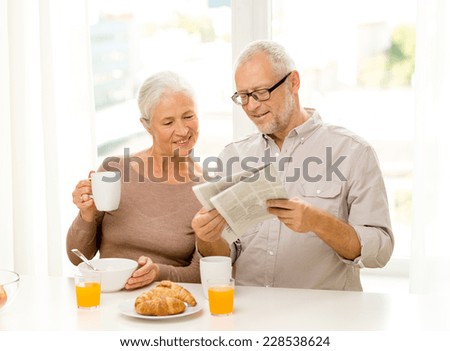 family, technology, food, drinks and people concept - happy senior couple having breakfast and reading newspaper at home