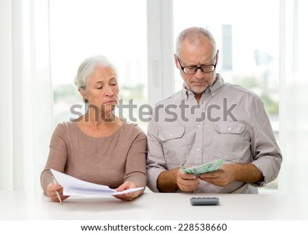 family, savings, age and people concept - senior couple with papers, money and calculator at home