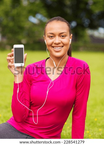 fitness, park, technology and sport concept - smiling african american woman with smartphone and earphones outdoors