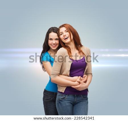 happiness, future, friendship and people concept - smiling teenage girls hugging over gray background with laser light