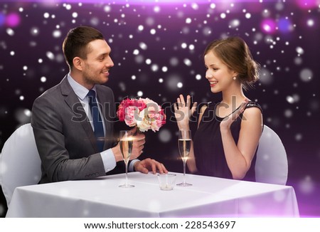 celebration, christmas, holidays and people concept - smiling couple with champagne and flowers at restaurant over night lights background