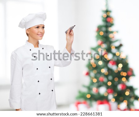 cooking, holidays, holidays, advertisement and people concept - smiling female chef with marker writing something on air over living room and christmas tree background