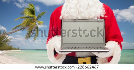 christmas, advertisement, technology, travel and people concept - close up of santa claus with laptop computer over tropical beach background