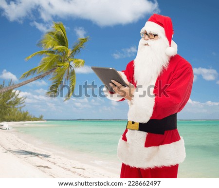 christmas, holidays, technology and people concept - man in costume of santa claus with tablet pc computer over tropical beach background