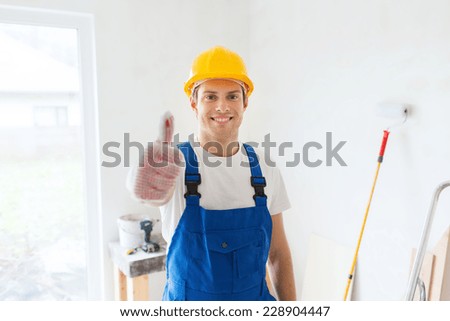 building, repair, gesture and people concept - smiling young builder in hardhat showing thumbs up indoors