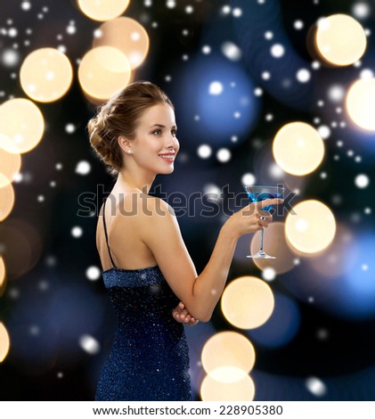 party, drinks, holidays, christmas and people concept - smiling woman in evening dress holding cocktail over night lights and snow background