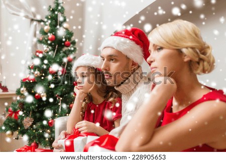 christmas, holidays, sadness and people concept - sad family in santa helper hats with gift boxes at home