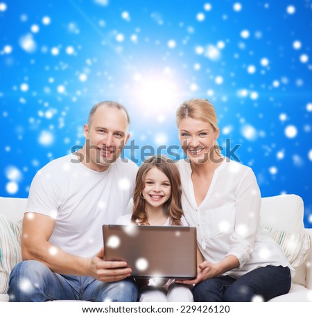 family, christmas, holidays, technology and people concept - smiling family with laptop computer over blue snowy background