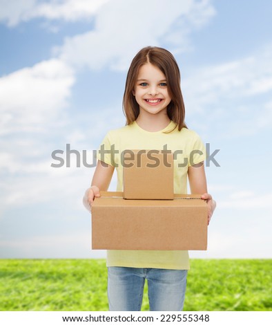 advertising, childhood, delivery, mail and people - smiling little girl holding cardboard boxes over natural background