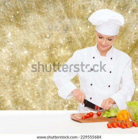 cooking, holidays, people and food concept - smiling female chef chopping vegetables over yellow lights background
