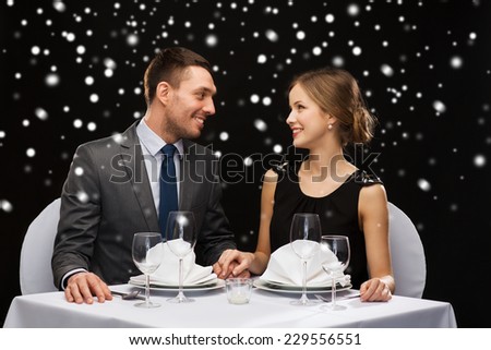 celebration, christmas, holidays and people concept - smiling couple at restaurant over black snowy background