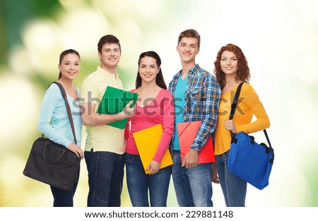 friendship, ecology, education and people concept - group of smiling teenagers with folders and school bags over green background