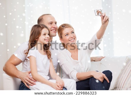 family, home, technology and people - happy family with camera taking picture over snowflakes background