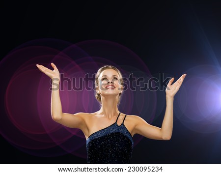 people, happiness, holidays and glamour concept - smiling woman raising hands and looking up over night lights background