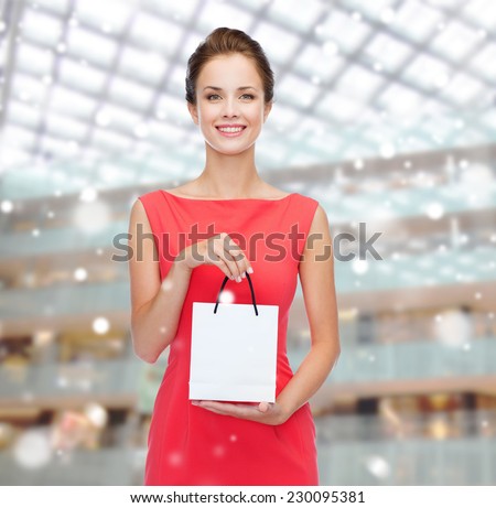 sale, gifts, holidays and people concept - smiling woman with white blank bag over shopping center background