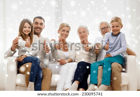 family, happiness, generation and people concept - happy family sitting on couch and showing thumbs up gesture at home