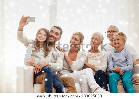 family, technology, generation and people concept - happy family sitting on couch and making selfie with smartphone at home