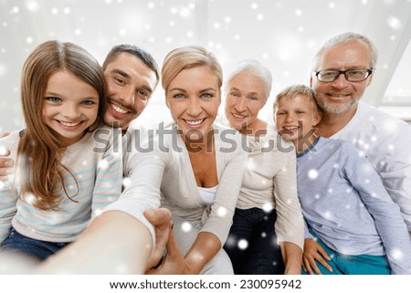 family, happiness, generation and people concept - happy family sitting on couch and taking selfie with camera or smartphone at home