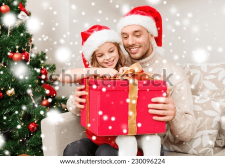 family, christmas, winter holidays, childhood and people concept - smiling father and daughter holding gift box at home