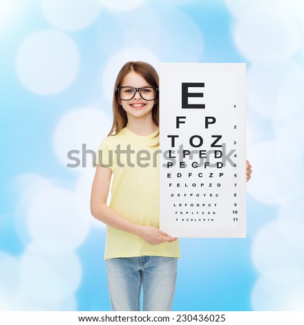 vision, health and people concept - smiling little girl wearing eyeglasses with eye checking chart