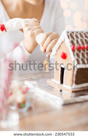 cooking, people, christmas and decoration concept - close up of woman making gingerbread houses at home