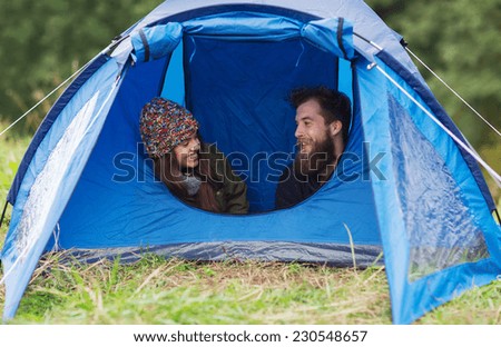 camping, travel, tourism, hike and people concept - smiling couple of tourists talking in tent