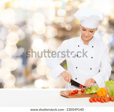 cooking, holidays, people and food concept - smiling female chef chopping vegetables over lights background
