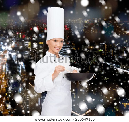 cooking, holidays, people and food concept - smiling female chef with pan and spoon mixing food over snowy night city background