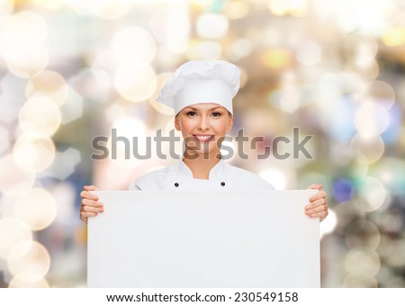 cooking, advertisement and people concept - smiling female chef, cook or baker with white blank board over holidays lights background