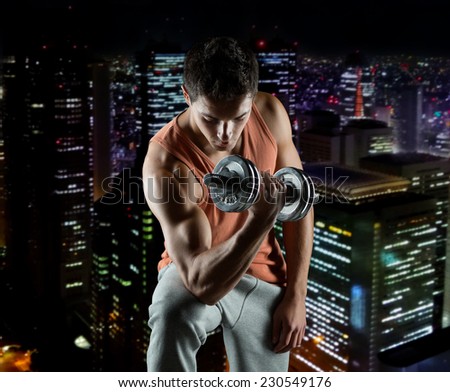 sport, bodybuilding, training and people concept - young man with dumbbell flexing biceps over night city background