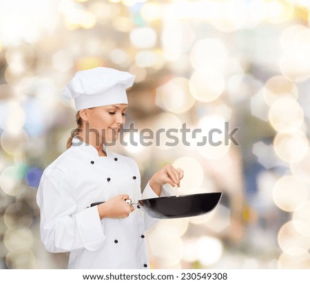 cooking, holidays, people and food concept - smiling female chef with pan and spoon mixing food over lights background
