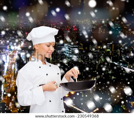 cooking, holidays, people and food concept - smiling female chef with pan and spoon mixing food over snowy night city background