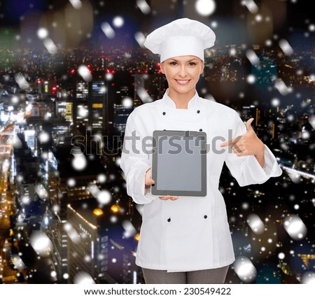 cooking, holidays, technology and food concept - smiling female chef, cook or baker with tablet pc computer pointing finger to blank screen over snowy night city background
