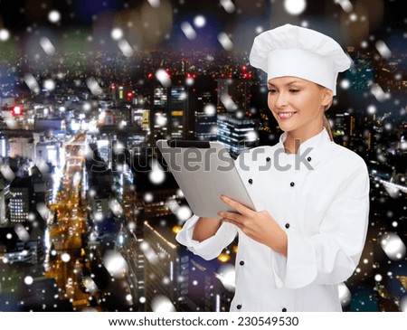 cooking, holidays, technology and people concept - smiling female chef, cook or baker with tablet pc computer over snowy night city background
