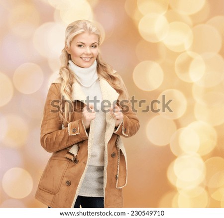 winter holidays, christmas, fashion and people concept - smiling young woman in winter clothes over beige lights background