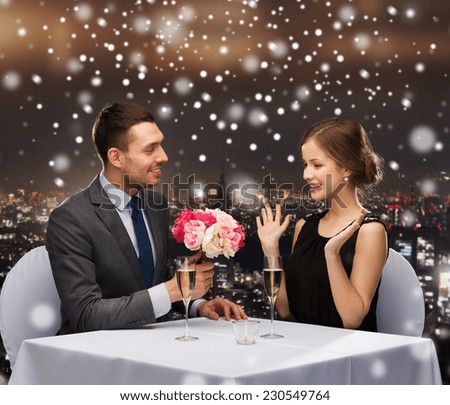 celebration, christmas, holidays and people concept - smiling couple with champagne and flowers at restaurant over snowy night city background