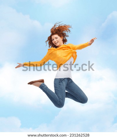 happiness, freedom, movement and people concept - smiling young woman jumping high in air over blue sky with cloud background