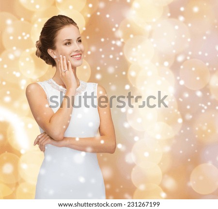 engagement, celebration, wedding and happiness concept - smiling woman in white dress wearing diamond ring over beige lights background and snow