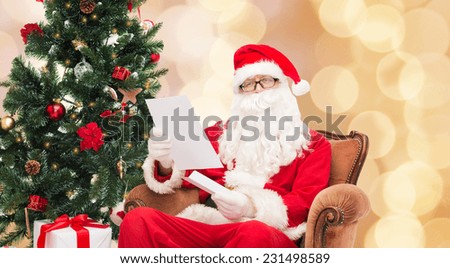 christmas, holidays and people concept - man in costume of santa claus with letter over beige lights background