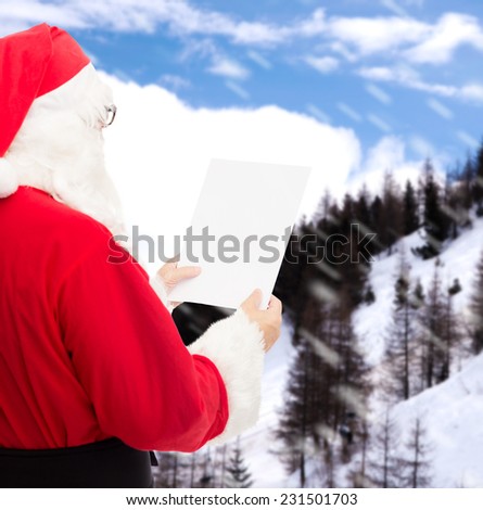 christmas, holidays and people concept - man in costume of santa claus reading letter over snowy mountains background
