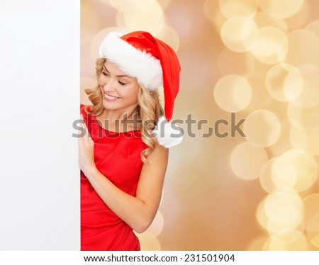 winter holidays, christmas, advertising and people concept - smiling young woman in santa helper hat with white blank billboard over beige lights background