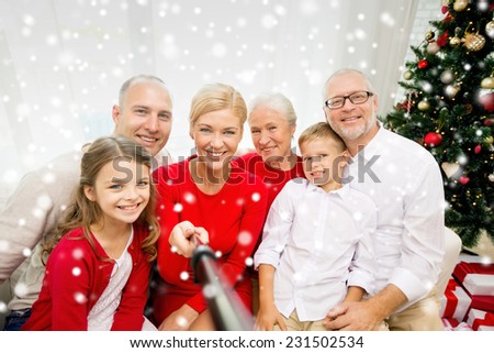 family, holidays, generation, christmas and people concept - smiling family with camera or smartphone and monopod taking selfie at home