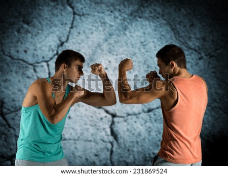 sport, competition, strength and people concept - young men fighting hand-to-hand over concrete wall background